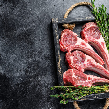 Bucăți de carne de oaie, într-o ramă din lemn, lângă un castron cu fructe de pădure